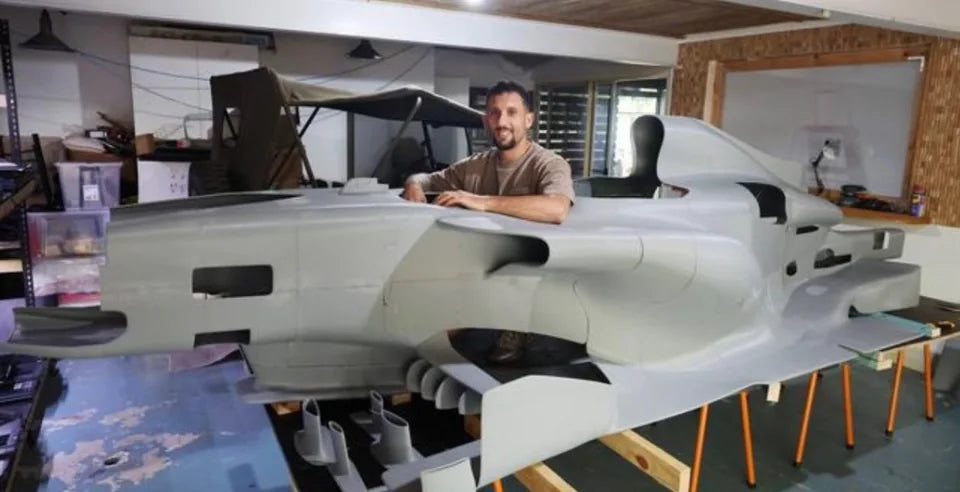 The full-size JRG Formula-inspired build in the workshop with a person beside the cockpit