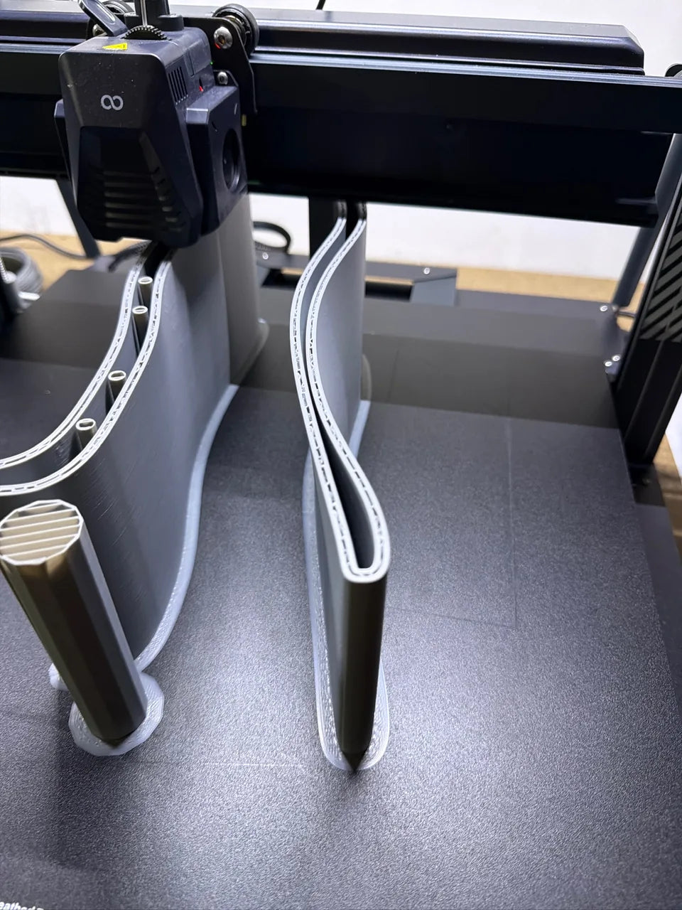 A 3D printer building a tall grey component layer by layer